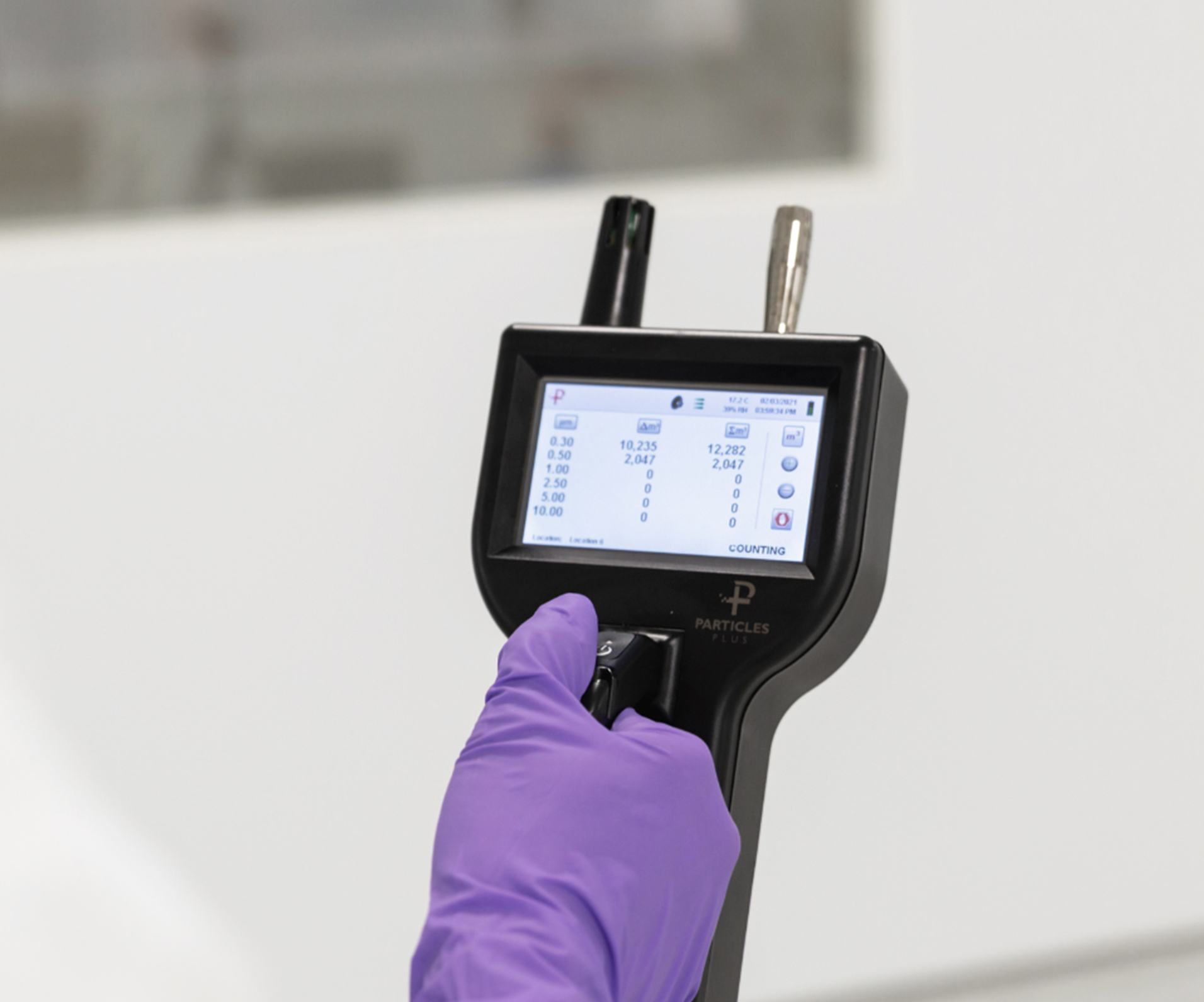 Particle counter held by a purple glove