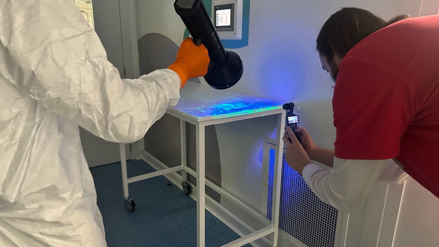 Cleanroom operator shining UV light on surface