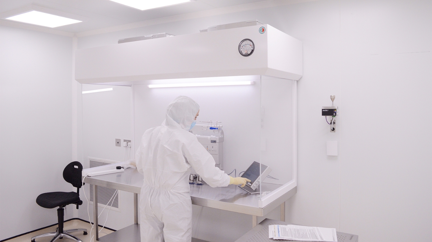 Cleanroom operator using a laminar flow cabinet in a GMP facility